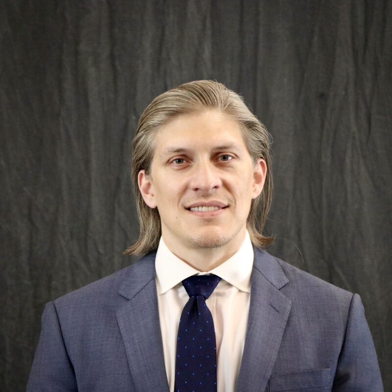 Photo of a male wearing a blue suit and dark tie